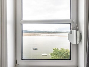 A window with a view of a calm body of water, a boat, and a tree. - 4 Bed in Aberdovey (oc-94232) (Aberdovey)