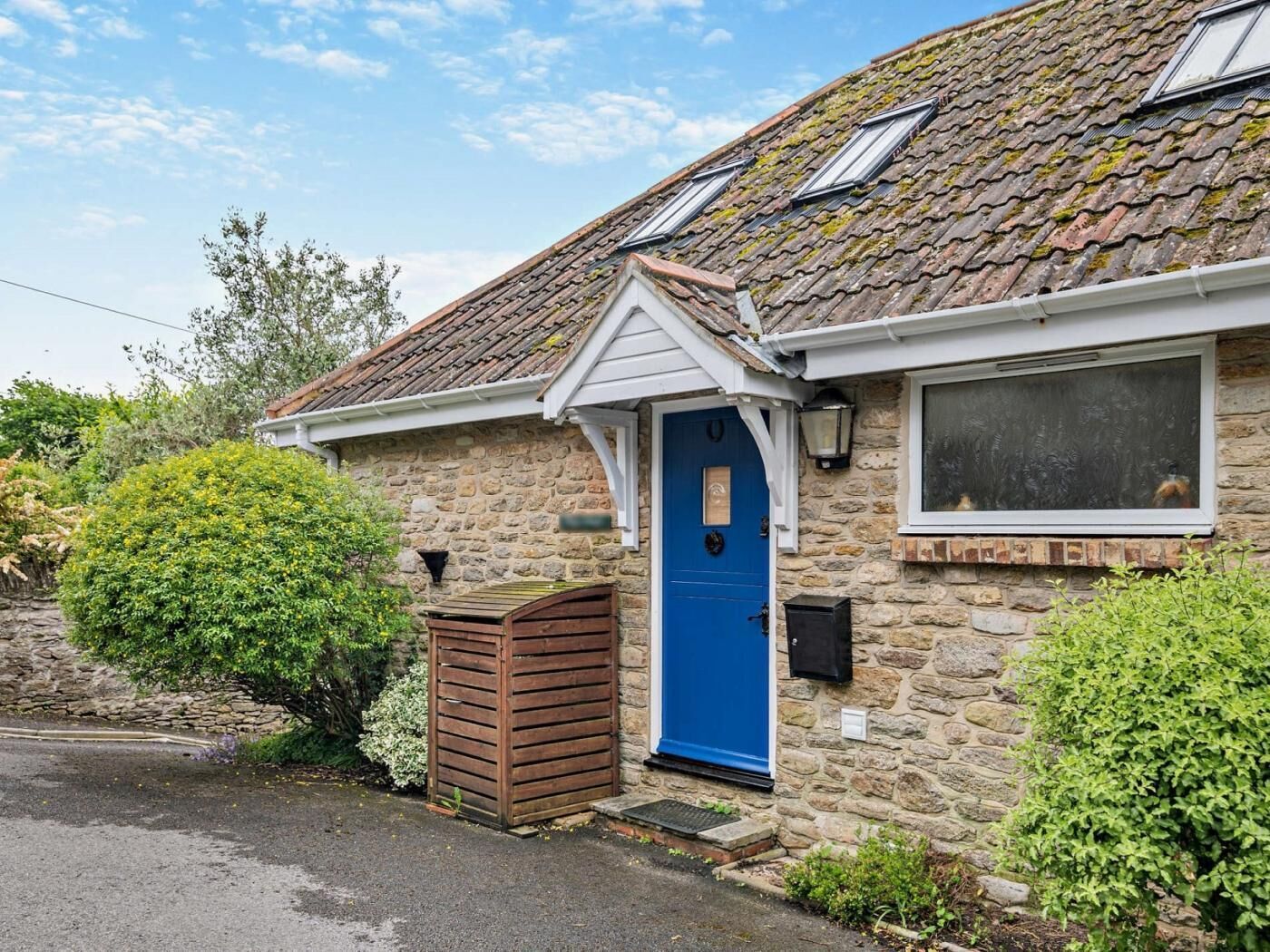 A stone house with a blue door, a small window, and a chimney.