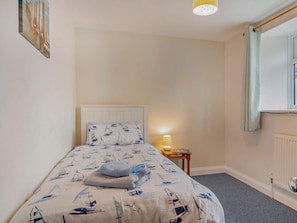 A bedroom with a bed, a bedside lamp, a window with curtains, and a radiator. - 2 Bed in Bridport (oc-94222) (Bothenhampton)