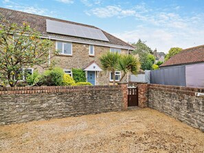 Une maison en pierre avec une allée en gravier et un petit jardin.