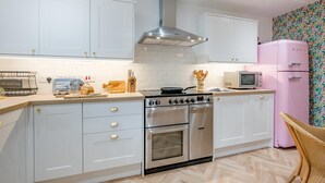 Una cocina moderna con armarios blancos, electrodomésticos de acero inoxidable y un refrigerador rosa.