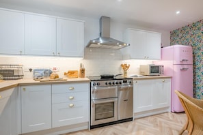 Eine moderne Küche mit weißen Schränken, Edelstahlgeräten und einem pinken Kühlschrank.