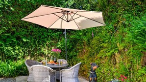 A patio with wicker furniture, a table with a drink, and a dog. - 1 Bed in Redruth (oc-90897) (Redruth)