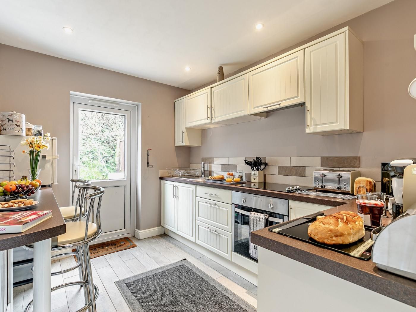 A modern kitchen with white cabinetry, a dining area with a table and chairs, and a view through the window.