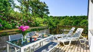 Eine Terrasse mit Tisch und Stühlen, umgeben von viel Grün.
