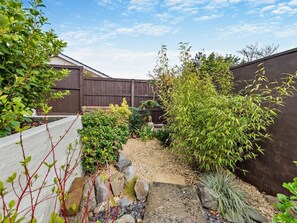 A garden with a variety of plants, a statue, and a wooden fence. - 2 Bed in Saundersfoot (oc-94207) (Saundersfoot)