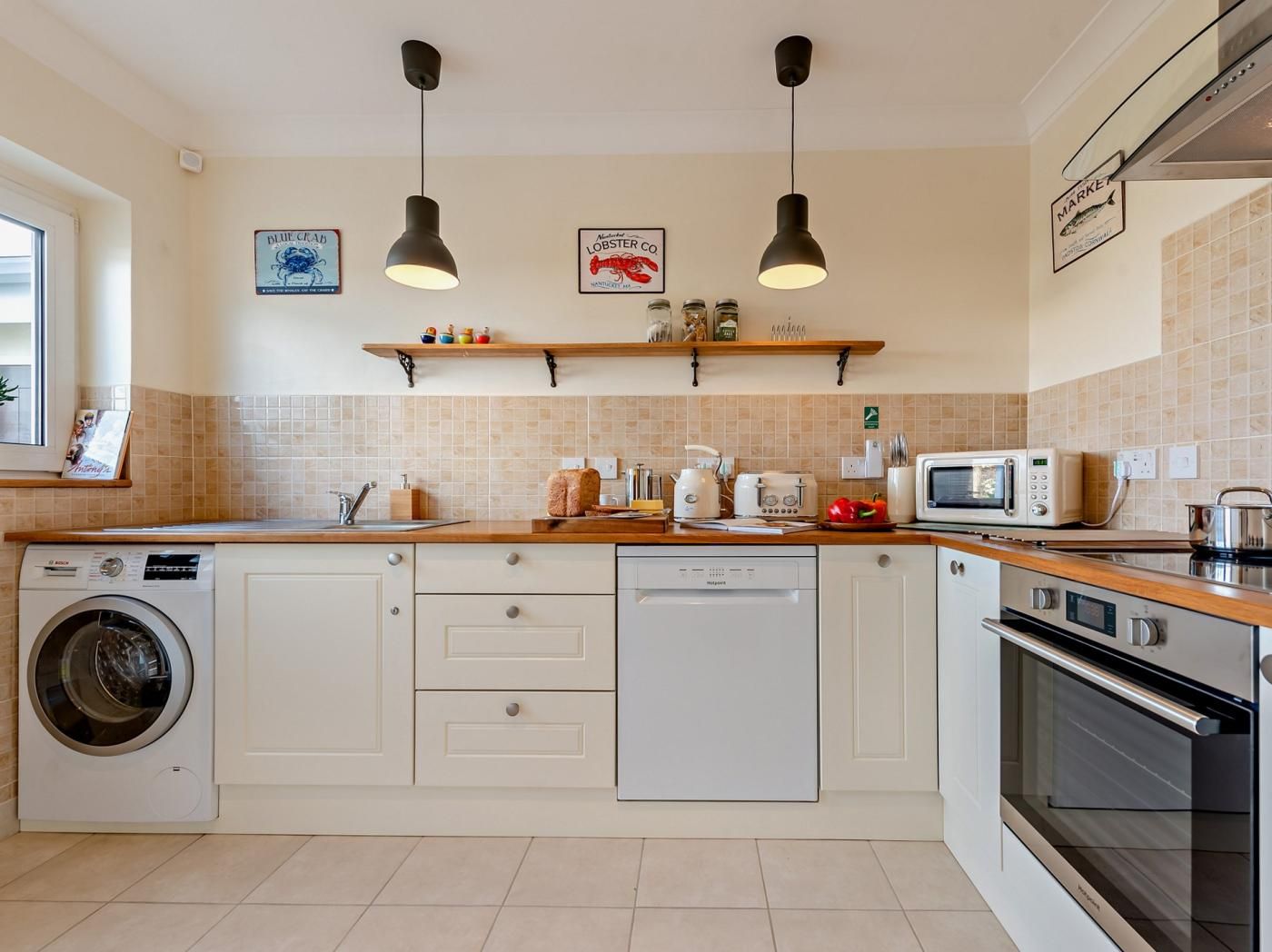 A modern kitchen with a washing machine, dishwasher, microwave, and oven.