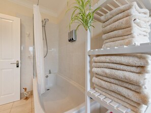 A bathroom with a shower, a towel rack with folded towels, and a small plant. - 2 Bed in Saundersfoot (oc-94207) (Saundersfoot)