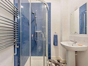 Een moderne badkamer met een douchecabine van glas, een wit wastafelmeubel en een handdoekrek.
