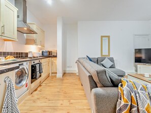 Ein kompakter Wohnbereich mit Küchenzeile, einer Couch und einem Fernseher.