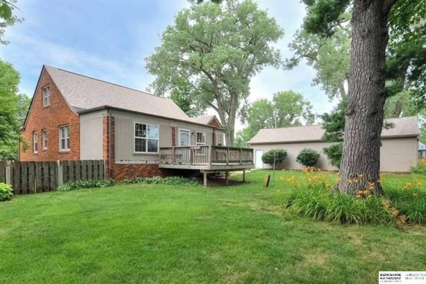 A two-story house with a brick exterior, a covered porch, and a well-maintained lawn.