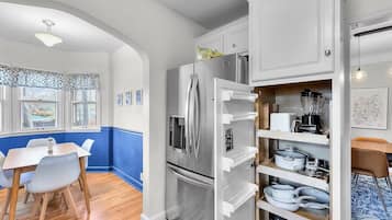 A kitchen with white cabinets, a built-in oven, and a refrigerator.