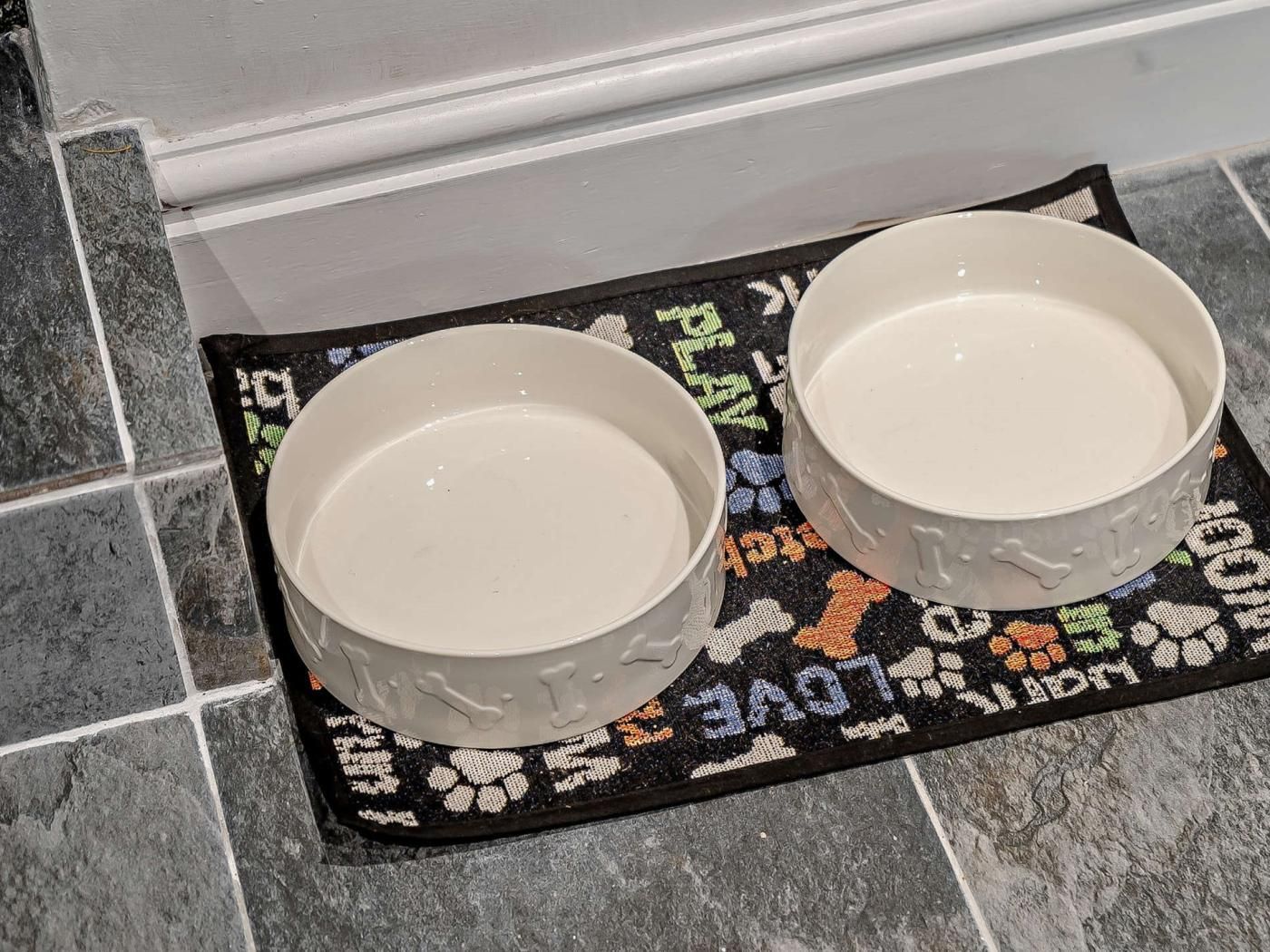Two white ceramic bowls on a black and colorful woven placemat with the words 'PLAY LOVE' visible.