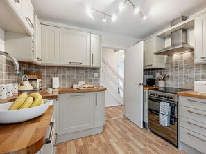 A modern kitchen with white cabinets, a wooden countertop, a stainless steel oven, and a tiled backsplash. - 3 Bed in Seaview (oc-94257) (Saint Helens)
