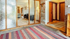 Ein geräumiger Flur mit Holzboden, einem Streifenmuster-Teppich und einer Steinwand.