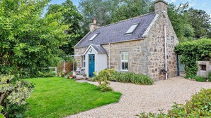 A stone house with a blue door, a gravel driveway, and a garden. - 1 Bed in Elgin (oc-94281) (Elgin)