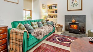 A cozy living room with a green sofa, a fireplace, a bookshelf, and a dining area. - 1 Bed in Elgin (oc-94281) (Elgin)