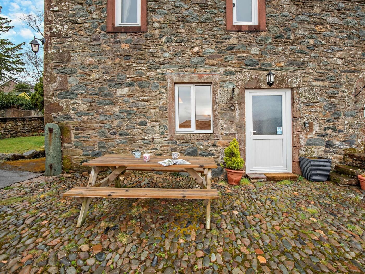A stone building with a wooden bench and a table, a door, and a window.