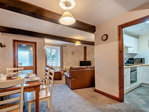 Ein gemütliches Wohnzimmer mit Kamin, ein Essbereich mit Tisch und Stühlen sowie eine Küche mit weißen Schränken und einer Mikrowelle.