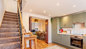 A staircase leading to a dining area with a table set for two, a kitchen with modern appliances, and a patterned rug on the floor. - 2 Bed in Middlesbrough (oc-94220) (Great Broughton)