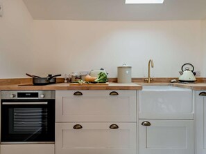 Een keuken met een fornuis, oven, spoelbak en diverse keukenbenodigdheden.