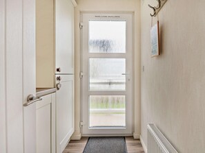 Ein Flur mit einer weißen Tür, einem Heizkörper und einem an der Wand hängenden Bild.