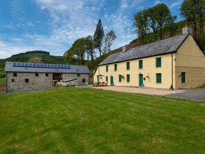 A stone building with a sloped roof and a yellow building with green windows. - 6 Bed in Llanwrtyd Wells (oc-bn259) (Treflys)