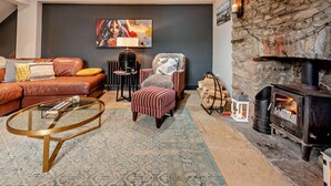 Una sala de estar con sofá, sillón, mesa de centro, chimenea y un cuadro en la pared.