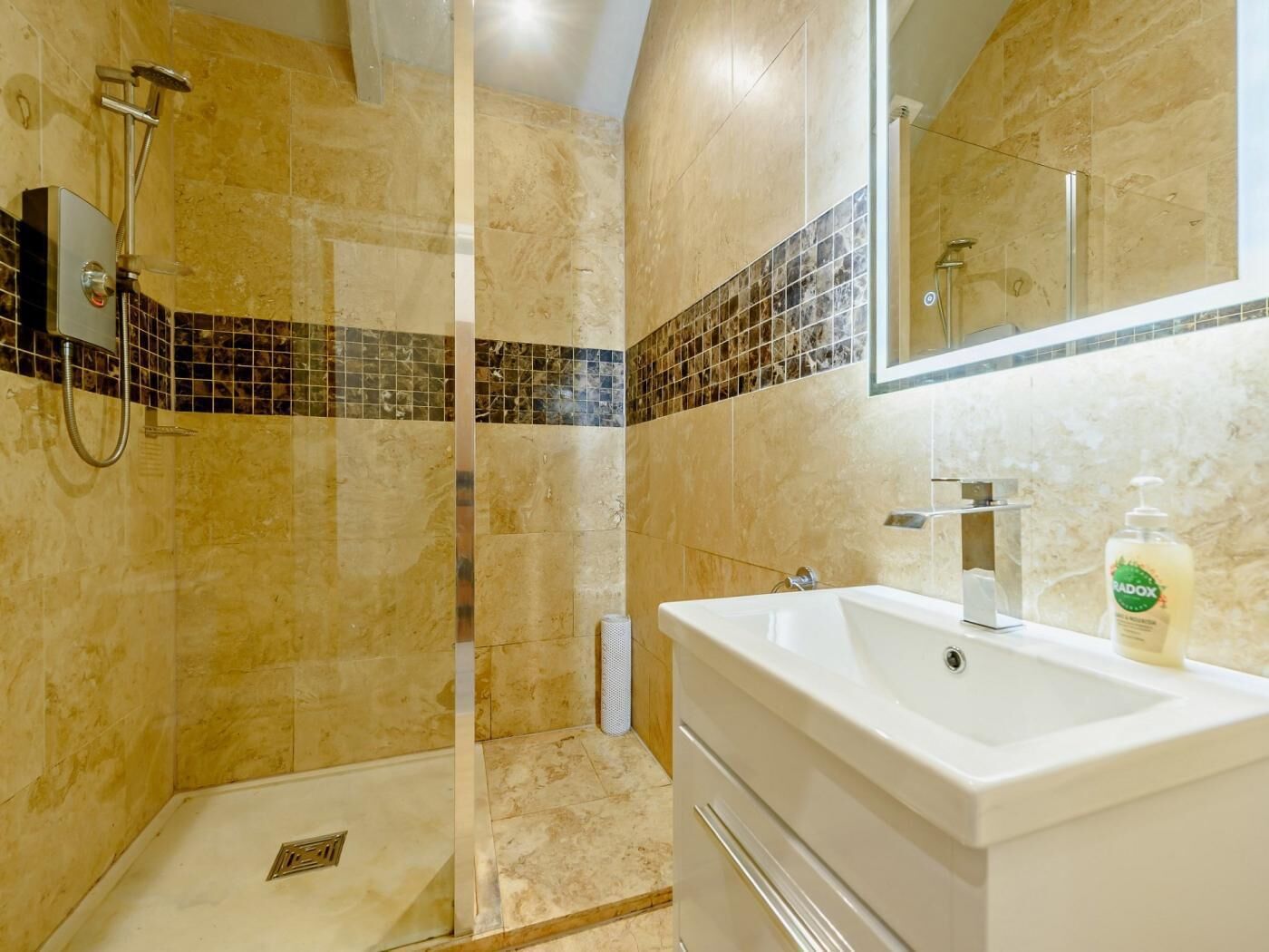 Un bany amb dutxa, un lavabo i un mirall.