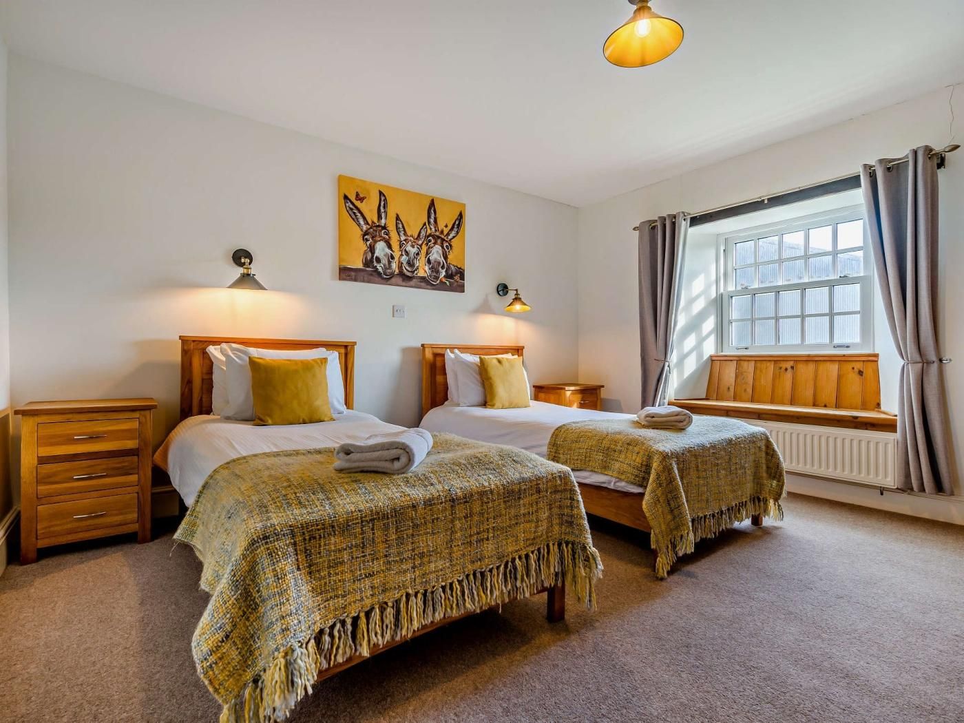 Une chambre d’hôtel avec deux lits, une fenêtre avec des rideaux, un radiateur et un tableau au mur.
