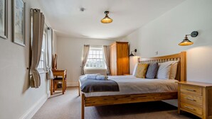 Un dormitorio con cama de madera, mesitas de noche, un armario y una ventana con cortinas.