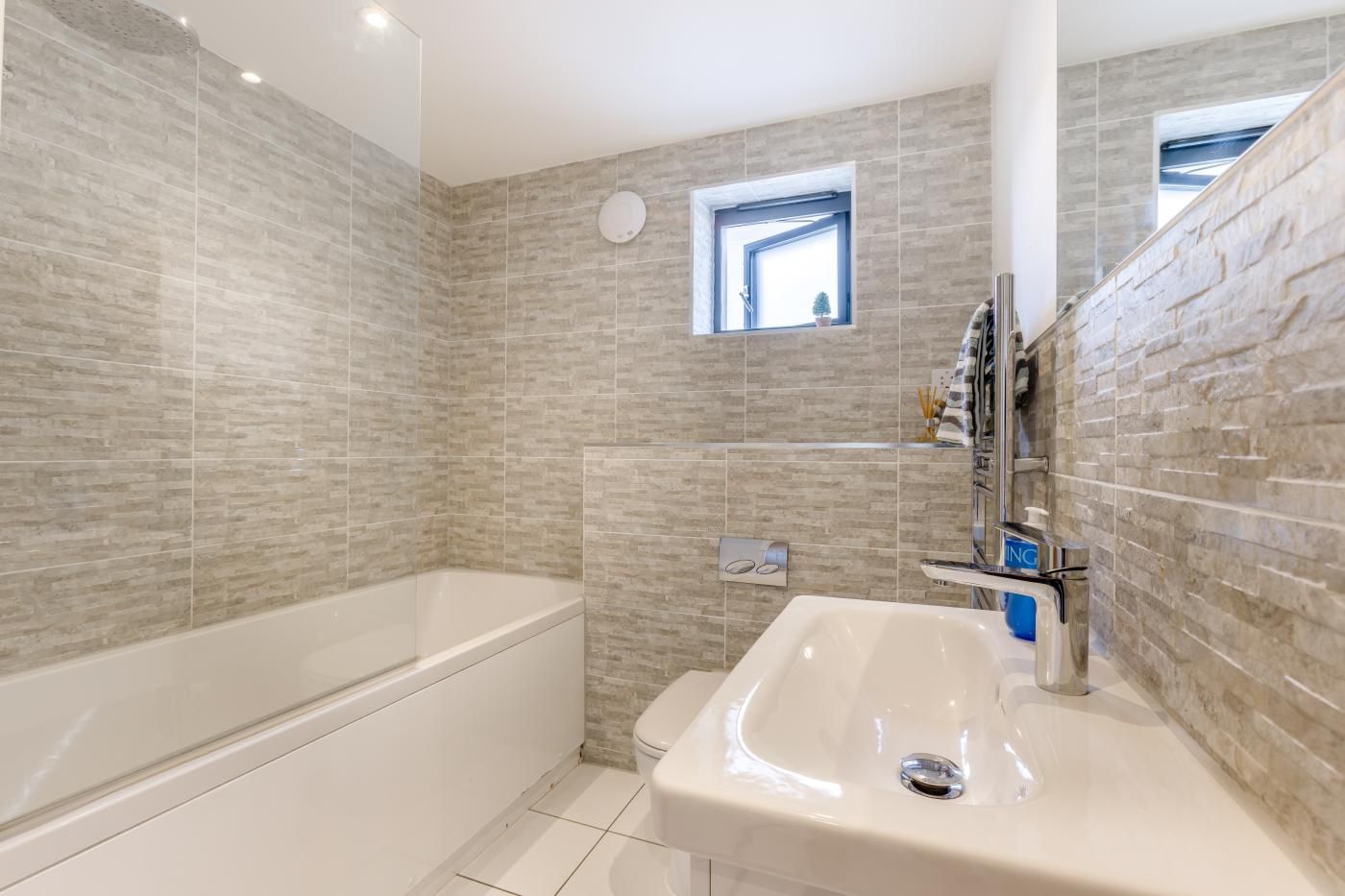 A bathroom with a bathtub, a sink, and a window.