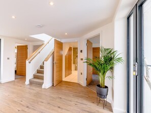 A modern interior with a wooden staircase, a potted plant, and a door leading to another room. - 4 Bed in Bideford (oc-74251) (Northam)