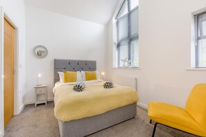 A bedroom with a bed, bedside table, lamp, and a window with blinds. - 4 Bed in Bideford (oc-74251) (Northam)