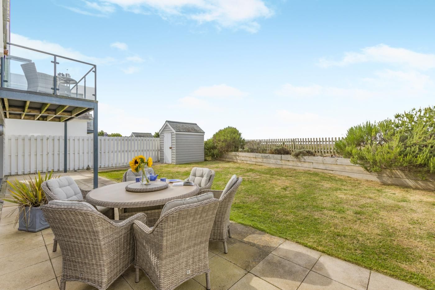 A patio with wicker furniture, a round table, and a vase with flowers.