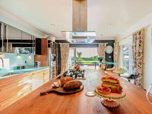 Eine moderne Küche mit einer Holzausziehtheke, einem Esstisch mit Kuchen und Blick ins Freie.