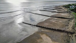 A coastal area with a wooden jetty extending into the water, a clear sky, and a distant shoreline with buildings. - 4 Bed in Bognor Regis (oc-81446) (Bognor Regis)