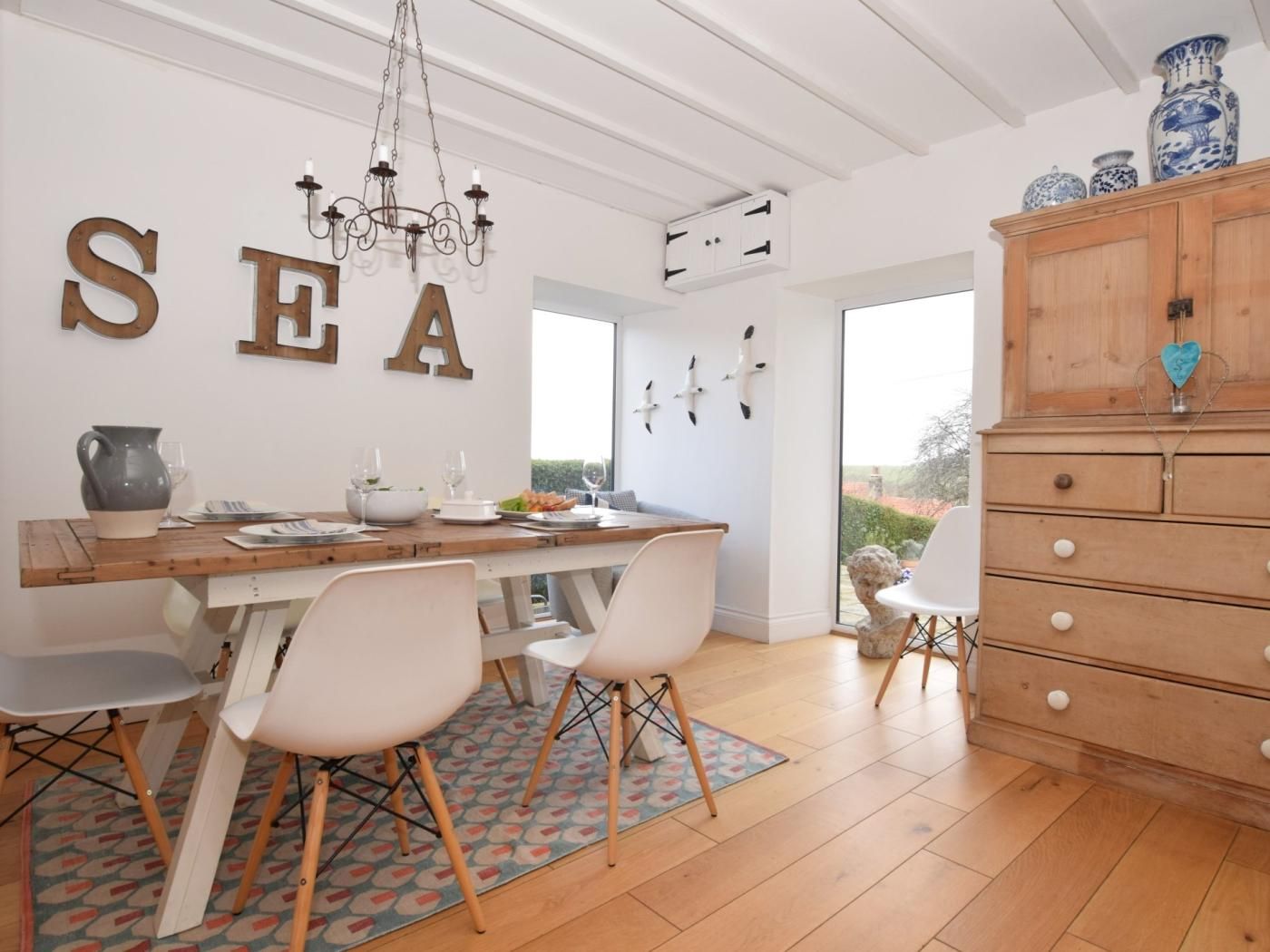 A dining area with a wooden table, white chairs, and a chandelier.