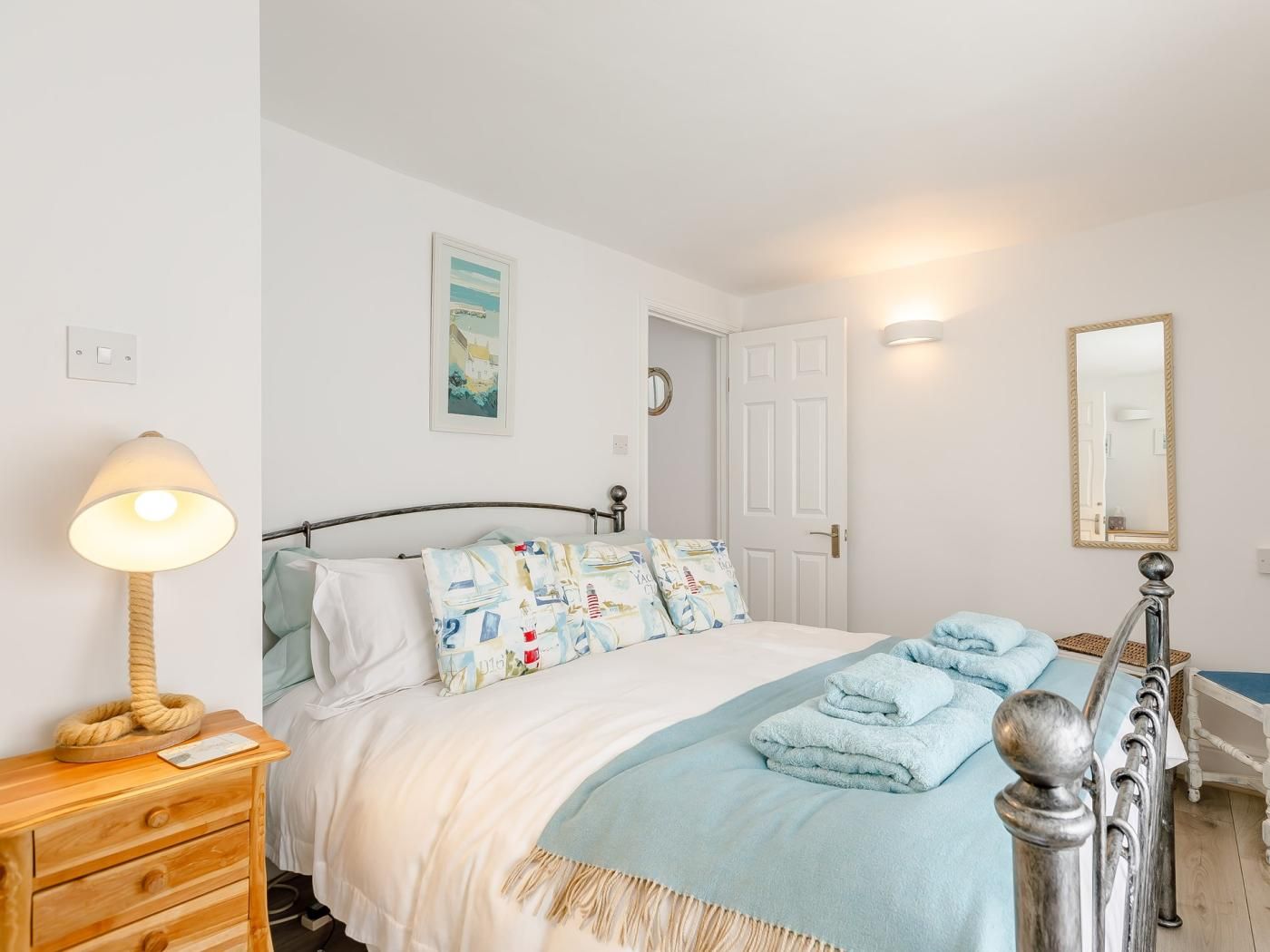 A bedroom with a bed, a bedside lamp, a dresser, a door, and a mirror.