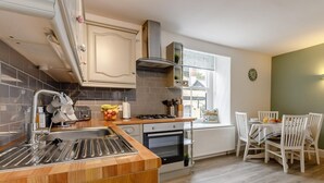 Una cocina con encimera de madera, un fregadero, una estufa y una zona de comedor con mesa y sillas.