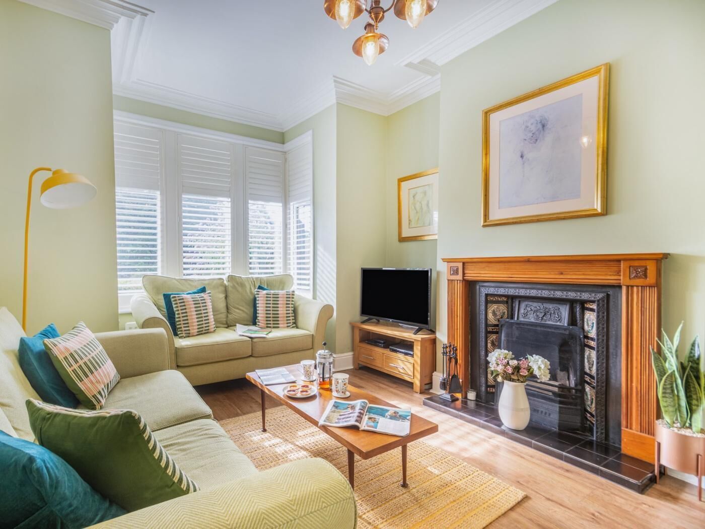 A living room with a sofa, coffee table, fireplace, television, and a framed picture on the wall.
