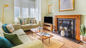 Una sala de estar con sofá, mesa de centro, chimenea, televisor y un cuadro en la pared.