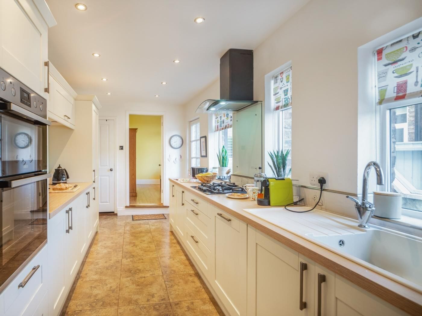 A modern kitchen with white cabinets, a stainless steel oven, a gas stove, and a sink.