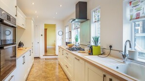 Una cocina moderna con gabinetes blancos, un horno de acero inoxidable, una estufa a gas y un fregadero.