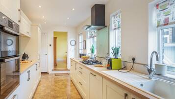 A modern kitchen with white cabinets, a stainless steel oven, a gas stove, and a sink.