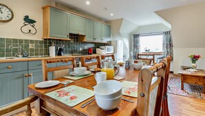 A kitchen with a dining area, wooden chairs, a table set with plates and bowls, and a clock on the wall. - 3 Bed in Perth (oc-50031) (Stanley)