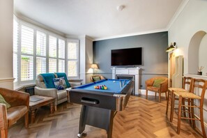 A pool table in a living room with a TV above it, a fireplace, and a bar area with chairs. - 8 Bed in Hunstanton (oc-89469) (Hunstanton)