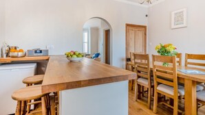 Une cuisine avec un îlot central en bois, une radio et un saladier rempli de fruits.