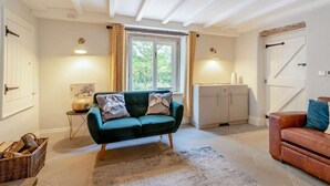 A cozy living room with a green sofa, a brown leather sofa, a fireplace, and a window with curtains. - 2 Bed in Hope Valley (oc-88979) (Sheffield)