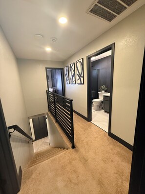 Eine Treppe führt zu einem Badezimmer mit Toilette, Waschbecken und einer Topfpflanze.